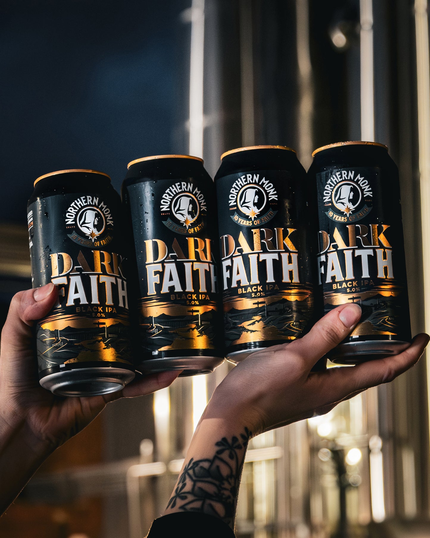 Four cans of 'Dark Faith' beer held up against a blurred background.