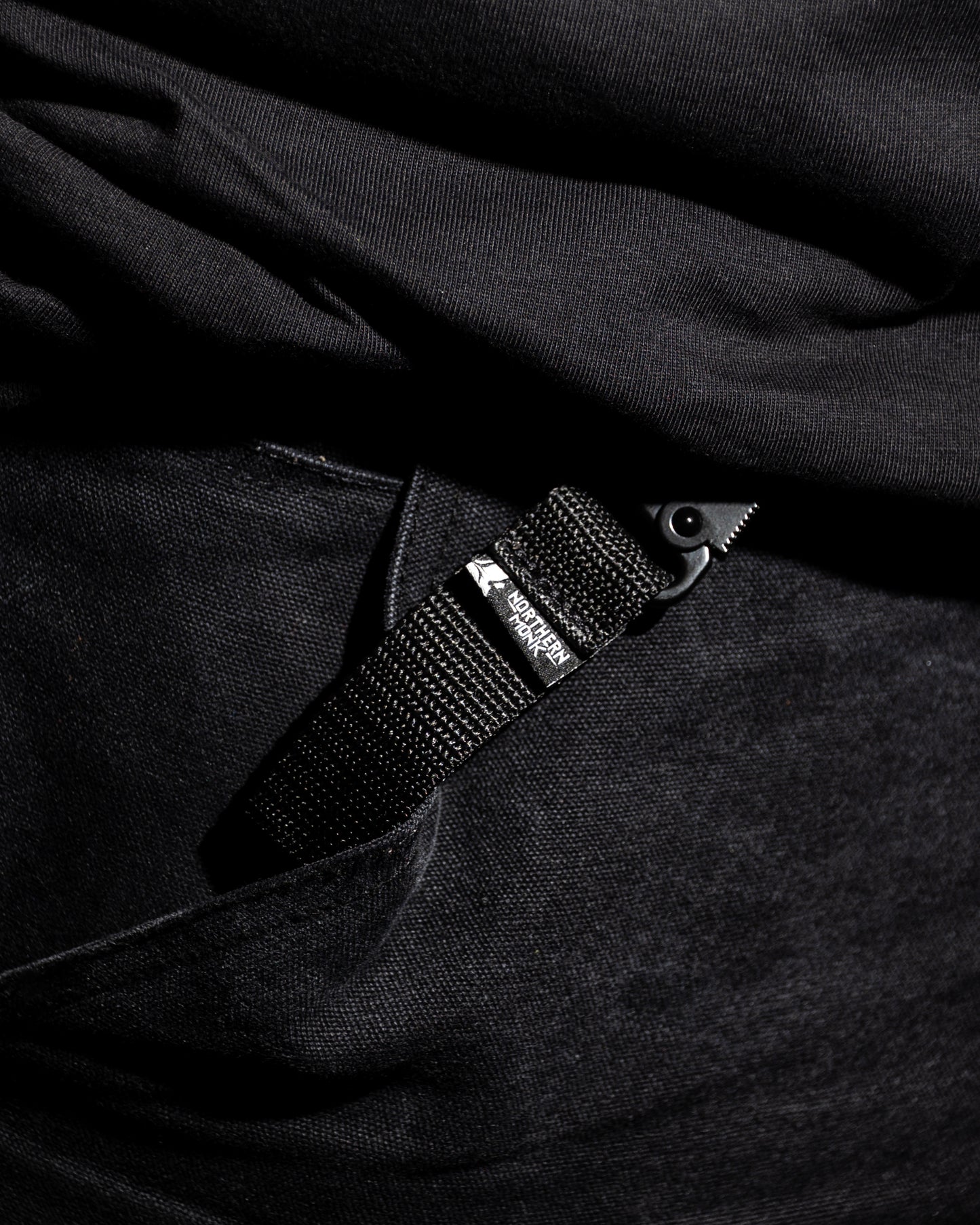Close-up of a black strap with a clip on a dark fabric background
