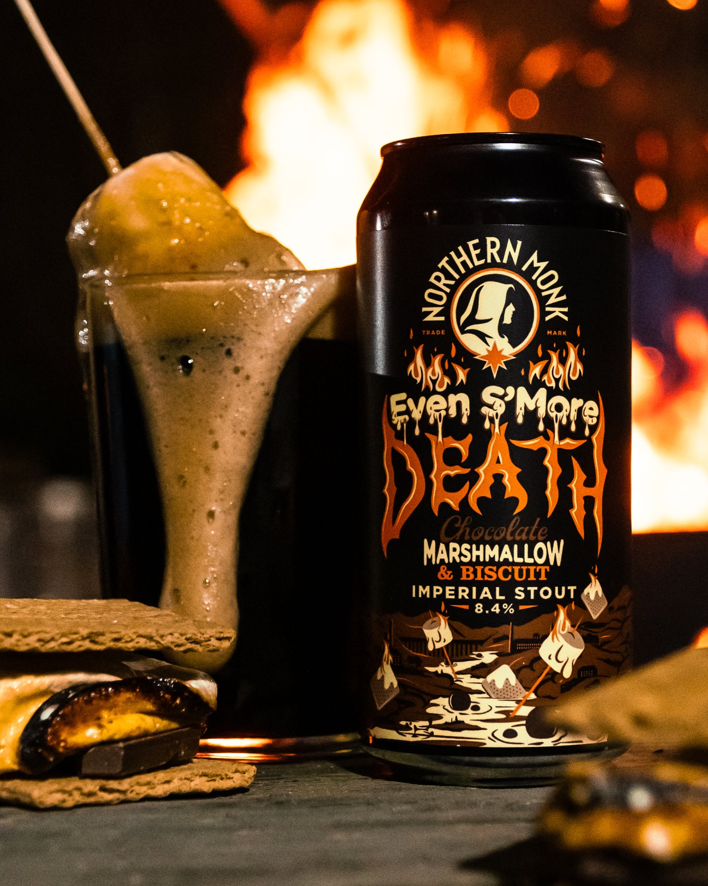 Can of Northern Monk 'Even S'More Death' Imperial Stout with marshmallow on a stick in front of a fire.