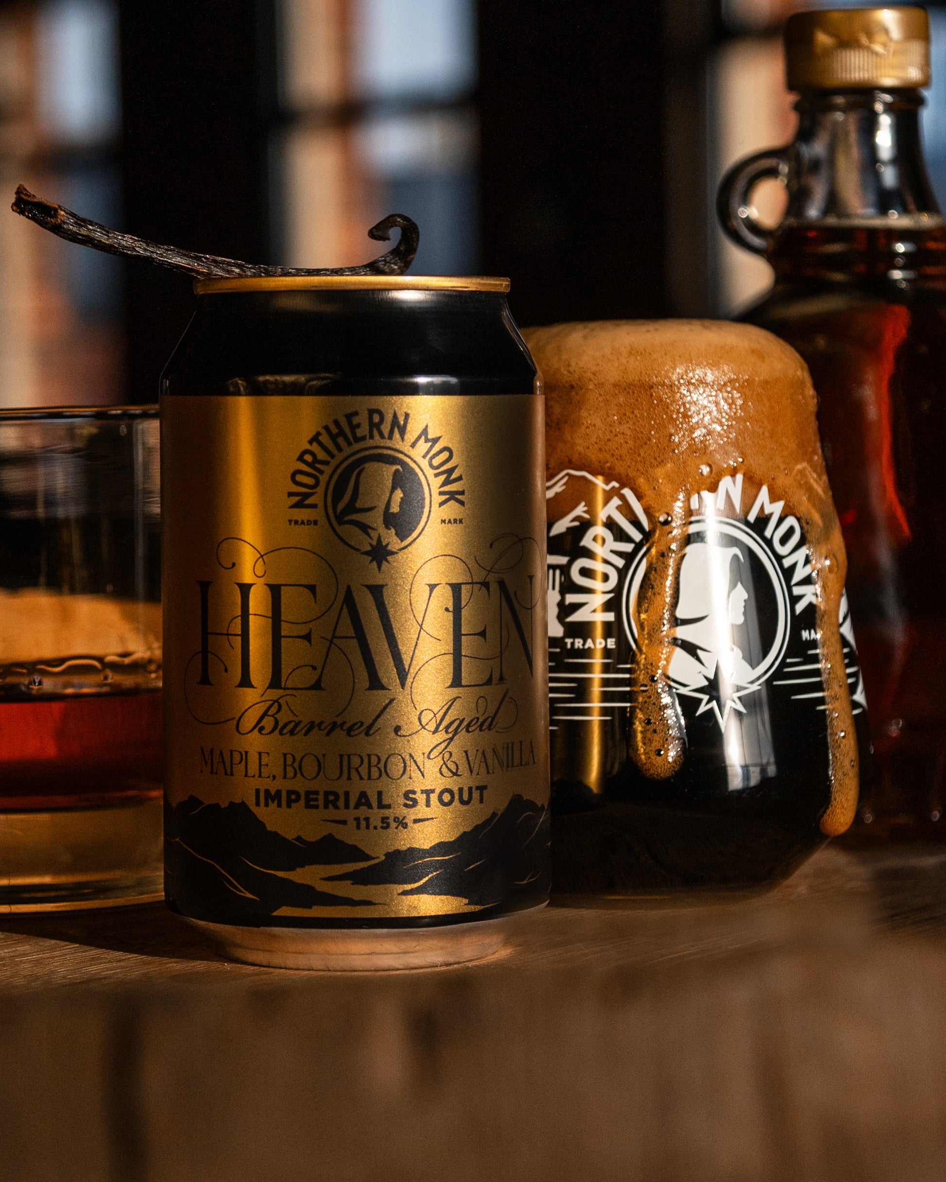 Can of Northern Monk Heaven Imperial Stout with a vanilla pod and maple syrup bottle in the background.